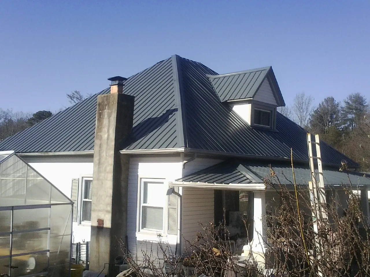 Dark blue standing seam metal roof on a white farmhouse with dormer — Slate & Tile Roof Repair by Roofing Brothers in Cranberry Township