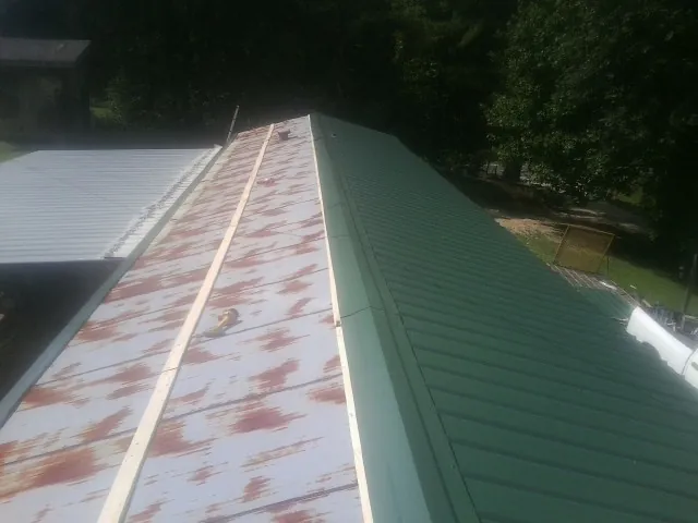 Old rusted panels beside newly installed green metal roofing — Wind Damage Roof Repair by Roofing Brothers in Cranberry Township