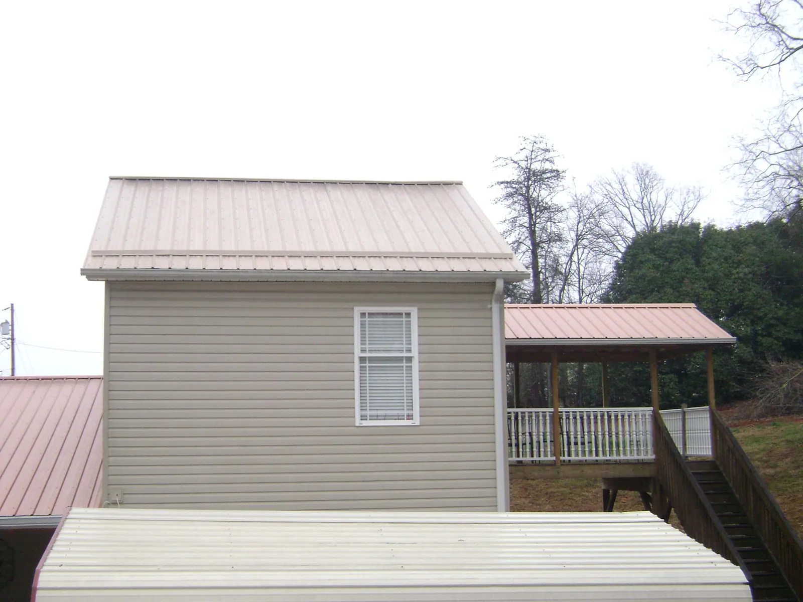 Tan metal roofs on a two story addition and attached porch, from a Roof Replacement job in Cranberry Township