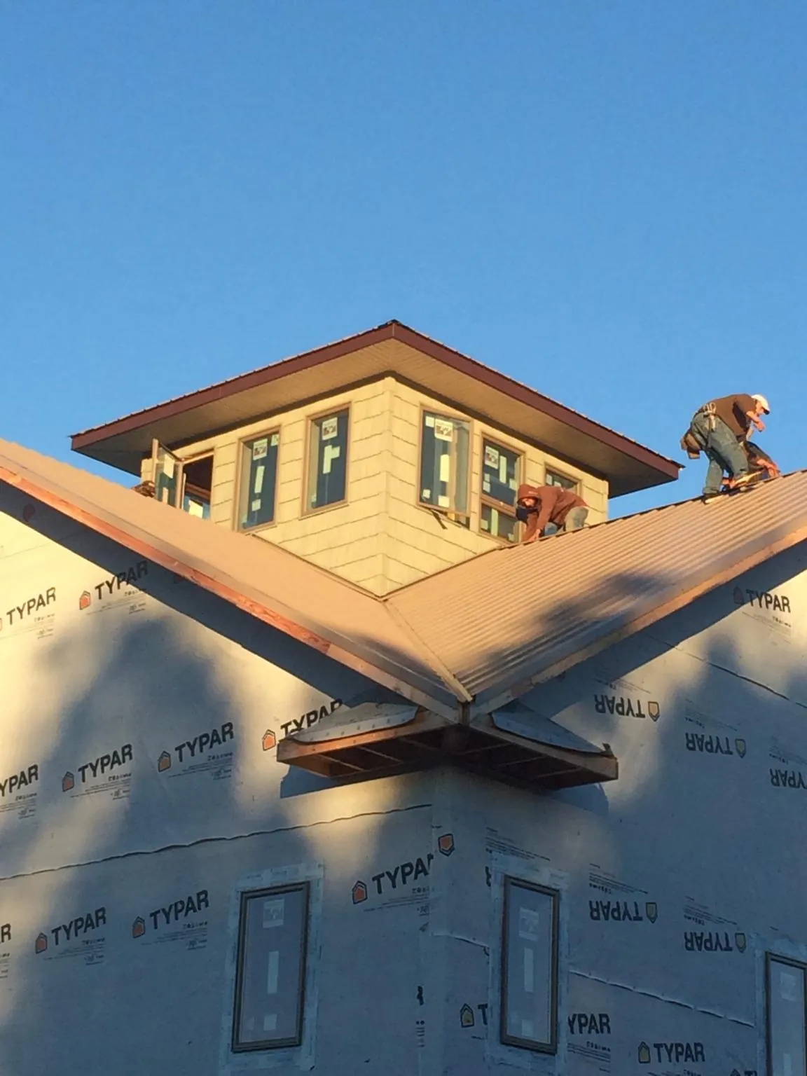 Roofers working around a rooftop cupola on a new metal roof at sunset — Roof Waterproofing in Cranberry Township by Roofing Brothers